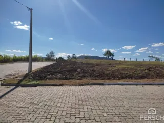 Vista externa de um terreno com grama e pavimento sob céu azul.