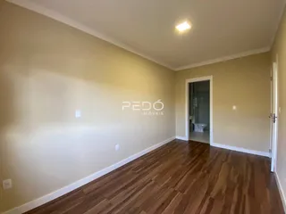 Interior de uma sala com piso de madeira e paredes claras.
