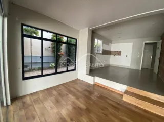 Vista interna de um ambiente com piso de madeira e grande janela.