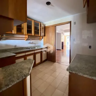 Vista da cozinha com armários de madeira e piso cerâmico.