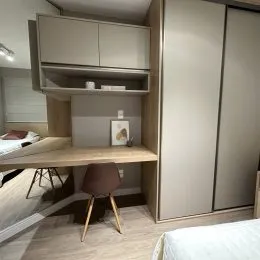 Quarto com cama e escrivaninha de madeira em um ambiente interno.