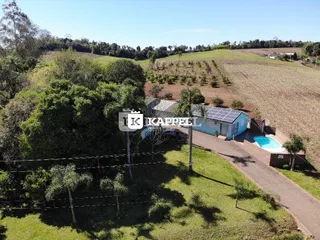 Foto externa mostrando uma piscina e uma estrutura ao ar livre em uma área verde.