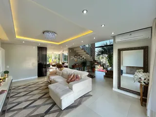 Sala de estar moderna com piso claro e sofá branco em um imóvel no Brasil.