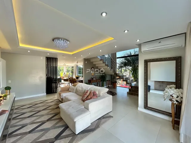 Sala de estar moderna com piso claro e sofá branco em um imóvel no Brasil.