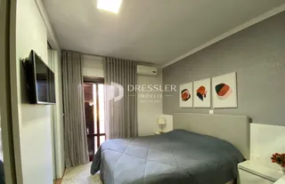 Quarto com cama e televisão montada na parede.