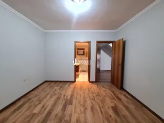 Ambiente interno de uma sala com piso de madeira e portas de acesso a outros cômodos.