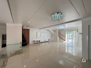 Interior de uma sala de estar ampla com piso de cerâmica clara e teto branco.