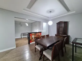 Sala de jantar com mesa de madeira e piso de madeira.