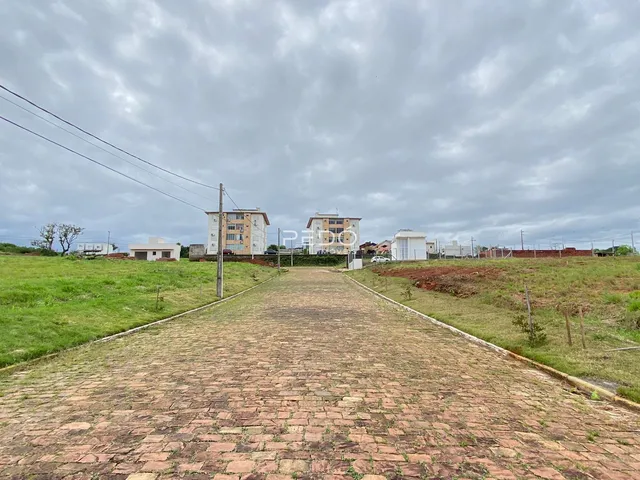 Vista de uma estrada pavimentada que se estende por uma área gramada com casas ao fundo.