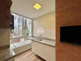 Vista da cozinha com bancada de granito e parede de tijolos aparentes.