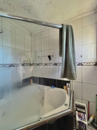 Foto interna de um banheiro com banheira e revestimento cerâmico branco.