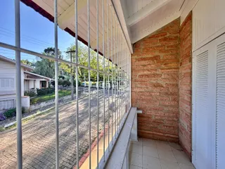 Vista lateral de uma propriedade com muro de tijolos e cerca de metal.