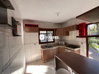 Uma cozinha com armários de madeira e bancada clara é visível na propriedade.