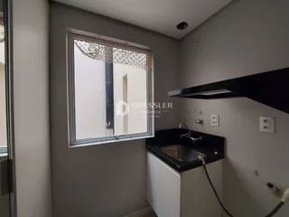 Vista de um banheiro com bancada escura e janela com tela de proteção.