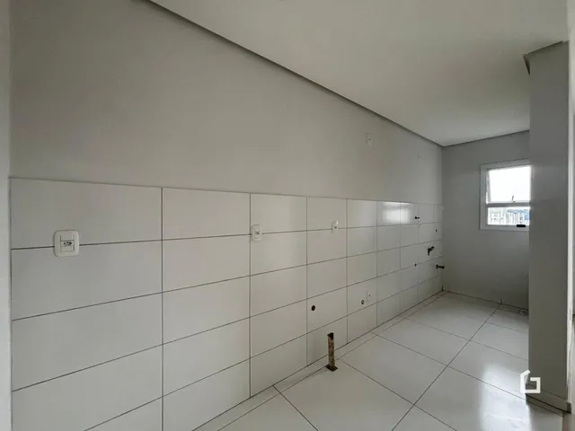 Vista interna de um corredor com paredes brancas e piso claro.
