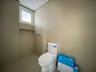 Banheiro simples com vaso sanitário branco e janela.