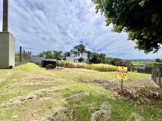 Vista externa de uma propriedade com gramado e vegetação ao redor.