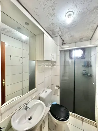 Foto interna de um banheiro com pia e box de vidro.