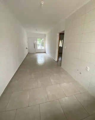 Corredor interno com piso de cerâmica clara e paredes brancas.