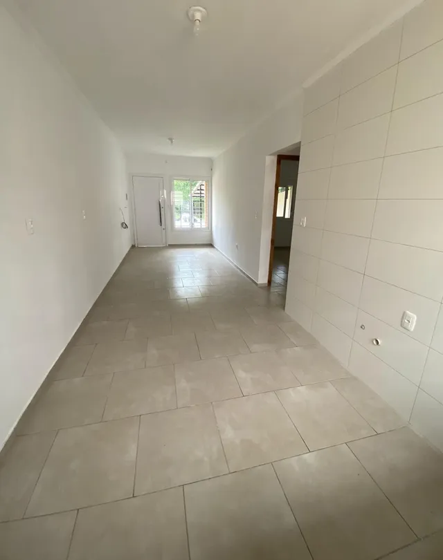 Corredor interno com piso de cerâmica clara e paredes brancas.