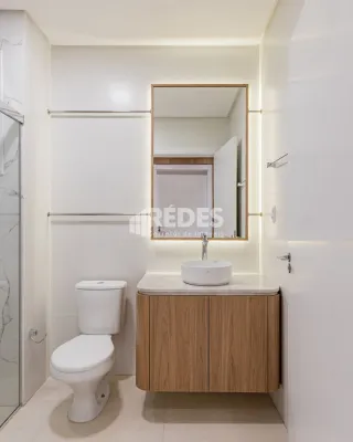 Foto de um banheiro moderno com louças brancas e bancada de madeira clara.