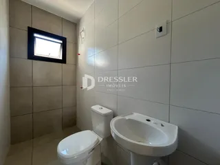 Foto de um banheiro com revestimento de cerâmica e louças sanitárias brancas.