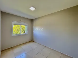 Ambiente interno de uma sala com piso de cerâmica e janela.