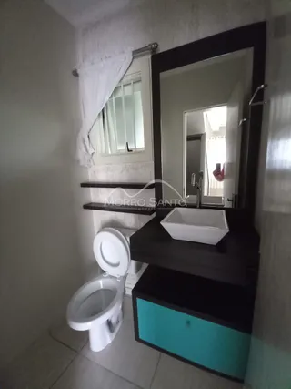 Foto de um banheiro mostrando um vaso sanitário e uma bancada escura.