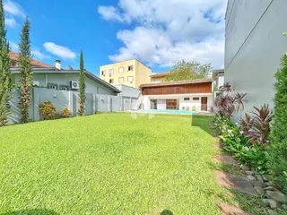 Vista externa de um quintal gramado com piscina e vegetação em Lajeado.
