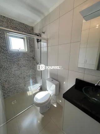 Banheiro com revestimento de azulejos e box de vidro.