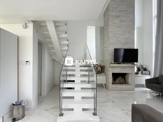 Sala de estar moderna com escadaria de vidro e lareira em ambiente claro.