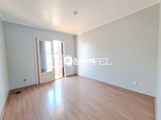 Sala de estar com piso de madeira clara e paredes brancas.
