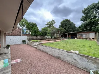 Vista externa da propriedade com jardim e muro de concreto.