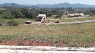Vista de uma área de terreno com vegetação rasteira e colinas ao fundo.