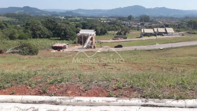 Vista de uma área de terreno com vegetação rasteira e colinas ao fundo.