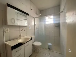 Um banheiro com revestimento cerâmico e box de vidro transparente.