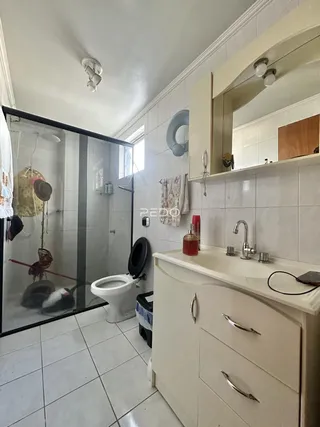 Foto do interior de um banheiro com piso de cerâmica e box de vidro.