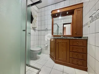 Foto de um banheiro com revestimento de azulejos brancos e armário de madeira.
