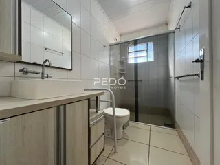 Foto de um banheiro com revestimento cerâmico e box de vidro.