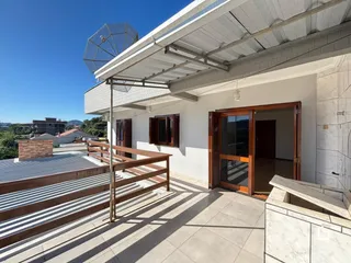 Vista externa de uma varanda com piso de cerâmica e grade de madeira em Lajeado, Brasil.