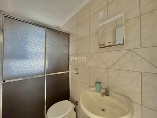 Foto de um banheiro interno com azulejos claros e louças sanitárias brancas.