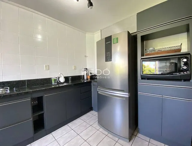 Cozinha moderna com armários escuros e revestimento branco.