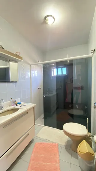 Banheiro com pia, box de vidro e vaso sanitário branco.