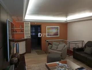 Sala de estar com piso de madeira e parede laranja em um imóvel no Brasil.