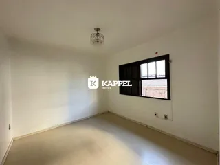 Sala de estar vazia com paredes brancas e piso claro.