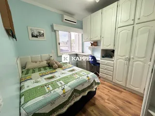 Quarto com cama e armários brancos em um ambiente claro.