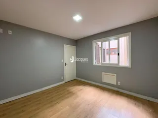 Ambiente interno de uma sala com piso de madeira clara e paredes cinzas.