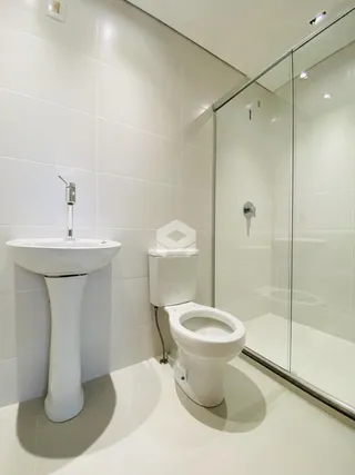 Banheiro com pia e vaso sanitário em cerâmica branca.