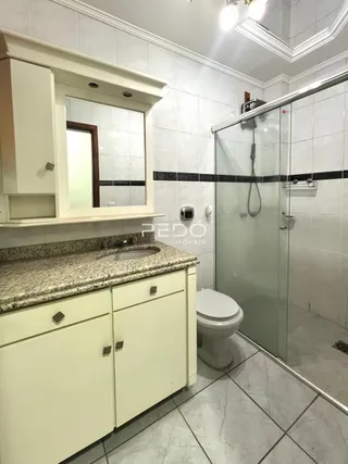 Foto de um banheiro com revestimento cerâmico e box de vidro.