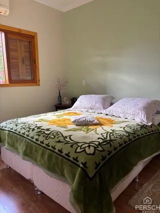 Quarto com cama coberta por um edredom verde e amarelo.
